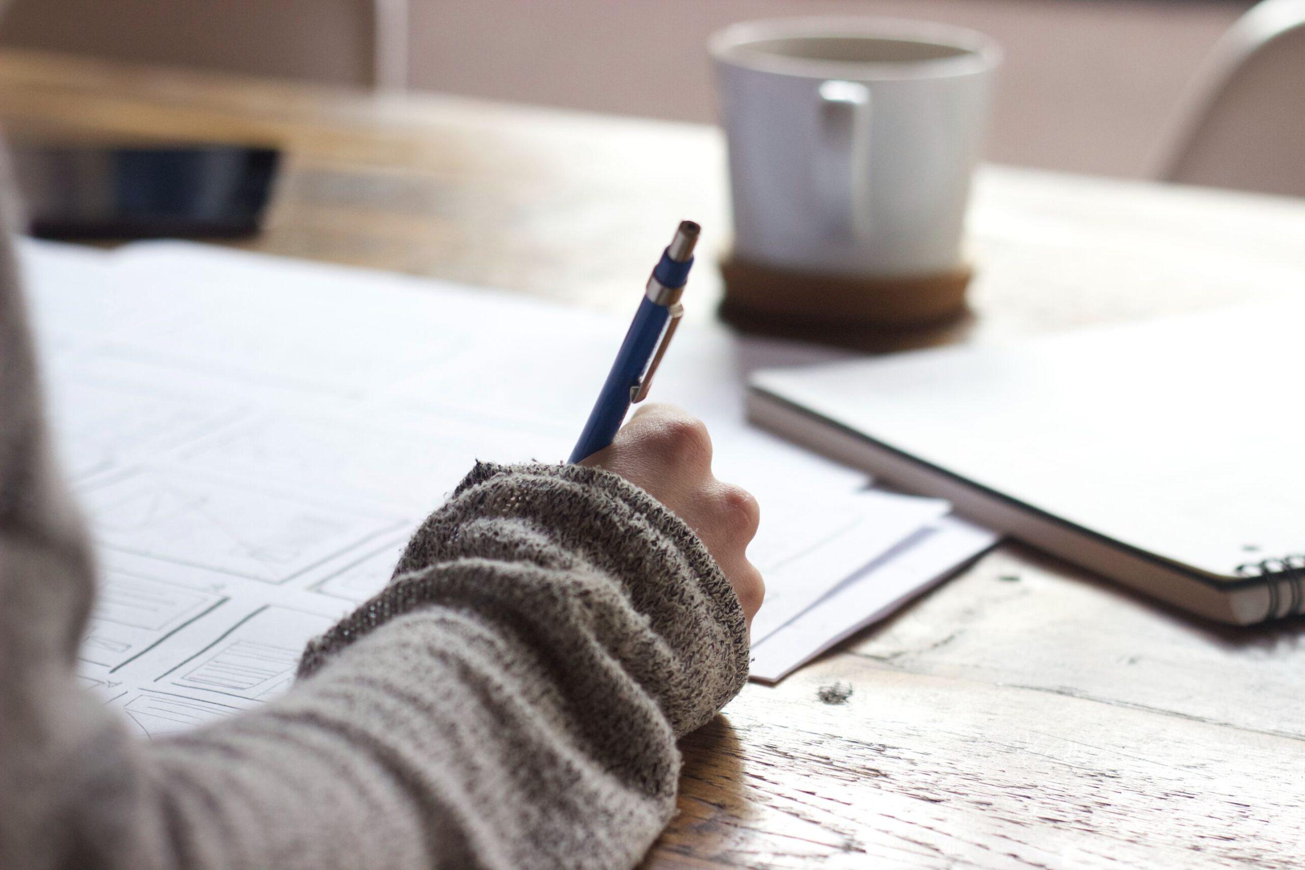 Person writing notes with a pen on a piece of paper.